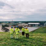 Four Syklo employees are standing on a hill, looking towards the circular economy center.