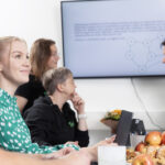 Personnel of Syklo are sitting in a break room and having a meeting.