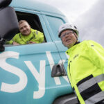 Two Syklo´s employee smiling at Hyvinkää circular economy hub. Other is inside the truck and other is standing infront of the truck.